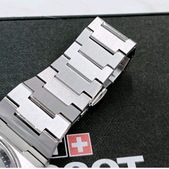 Silver watch strap on a black surface with a brand logo in the background