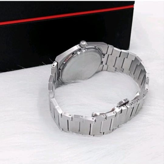 Silver watch on a white surface with a black and red background